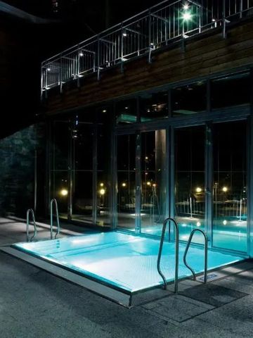 Kleiner Außenpool bei Nacht mit beleuchteter Glasfassade und Geländer