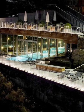 Hotel mit architektonisch ansprechender Terrasse und Außenpool bei Nacht