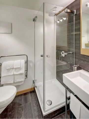 Modernes Badezimmer mit Glasdusche und weißen Handtüchern