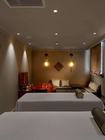 Gedimmtes Spa mit zwei Massage-Liegen und stilvoller Dekoration.