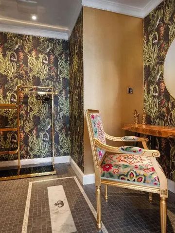 Opulent eingerichteter Vorraum mit stilvollem Sessel und kunstvollen Wandverzierungen