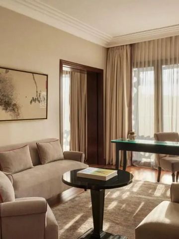 Elegantes Hotelzimmer mit Sofa und Schreibtisch vor großen Fenstern