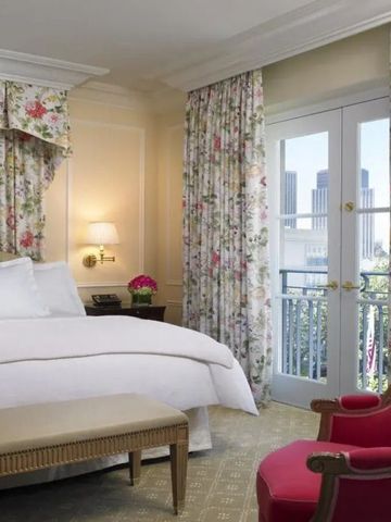 Schönes Zimmer mit Balkonzugang und floralen Vorhängen. Aussicht auf die Skyline