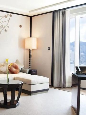 Lichtdurchflutete Hotelsuite mit Sofa und Blick auf die Stadtlandschaft