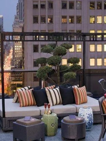Stilvolle Dachterrasse mit Sofas und Blick auf die Stadt bei Abenddämmerung