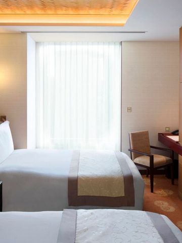 Helles Zweibettzimmer mit eleganter Einrichtung und großem Fenster.