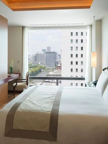 Luxuriöses Hotelzimmer mit Kingsize-Bett und Stadtblick durch große Fenster