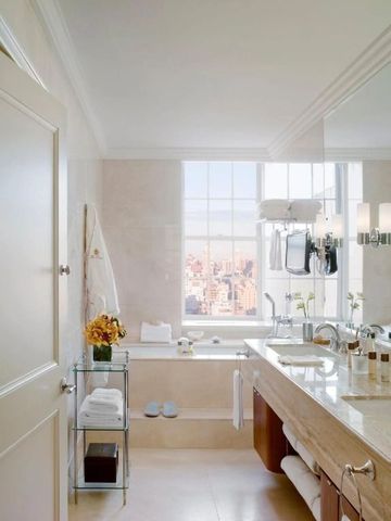 Elegantes Badezimmer mit Badewanne und großem Fenster mit Blick auf die Stadt