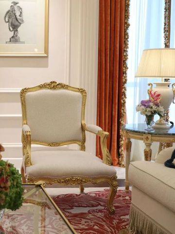 Eleganter Sitzbereich mit vergoldetem Sessel und Blumenarrangement im Hotelzimmer