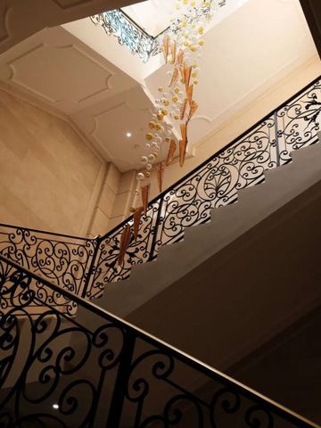 Elegantes Treppenhaus mit kunstvollem Geländer und moderner Beleuchtung