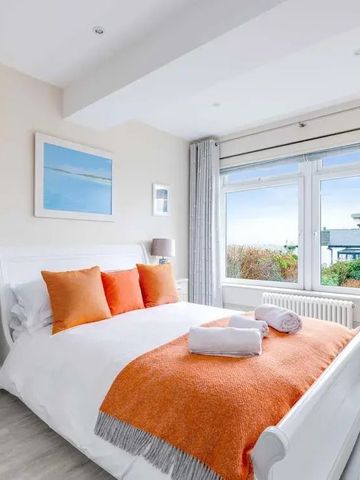 Geräumiges Schlafzimmer mit Doppelbett, orangefarbenen Akzenten und großem Fenster.