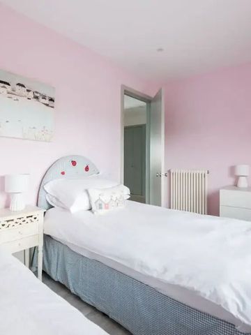 Helles Schlafzimmer mit zwei Einzelbetten und rosa Wänden