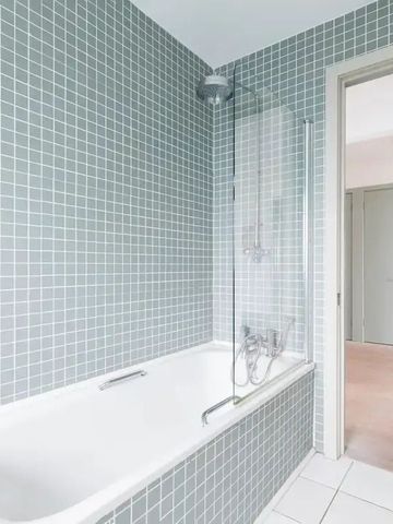 Badezimmer mit Badewanne und grünen Fliesen