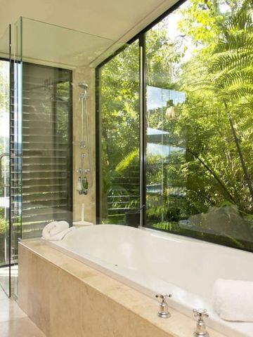Bibliothek mit großer Badewanne und Blick ins Grüne durch große Fenster