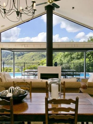 Luxuriöser Wohnbereich mit Panoramafenstern zu einem Pool und einer Hügelkulisse