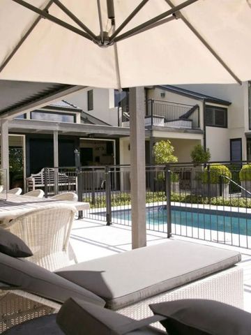 Sonnenterrasse mit Pool und bequemen Liegen unter einem Sonnenschirm