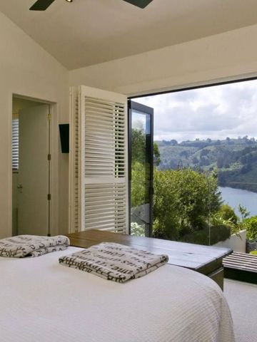 Schlafzimmer mit Panoramablick durch große Fenster auf eine grüne Flusslandschaft.
