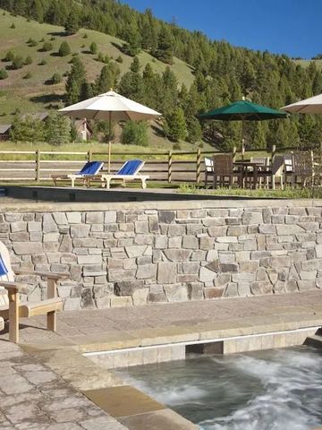 Außenbereich mit Steinmauer, Pool, Liegestühlen und grüner Landschaft im Hintergrund
