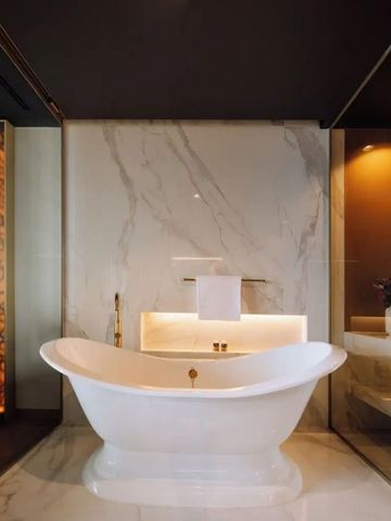 Freistehende Badewanne in luxuriösem Marmorbad mit raffinierter Beleuchtung.