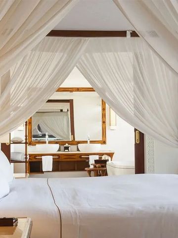 Helles Schlafzimmer mit Himmelbett und weißen Vorhängen.