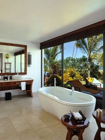 Luxuriöses Badezimmer mit freistehender Badewanne und Aussicht auf Garten