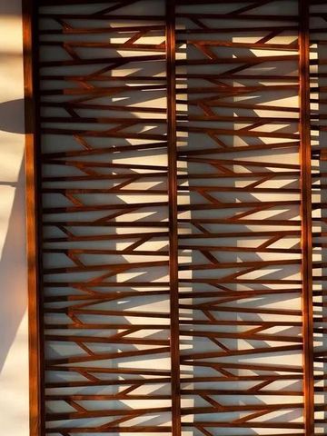 Sonnenlicht fällt durch kunstvolles Holzdekor an einer Wand