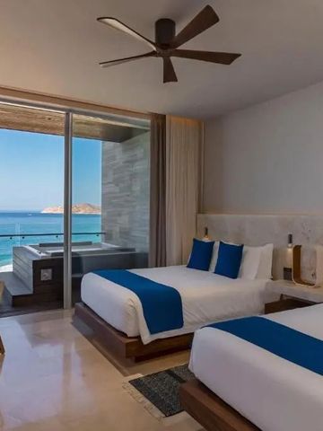 Helles Hotelzimmer mit zwei Doppelbetten und atemberaubendem Meerblick