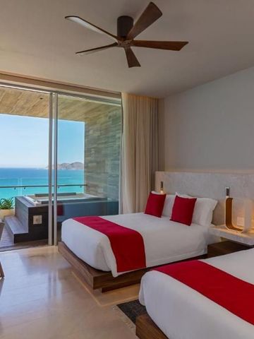 Hotelzimmer mit zwei Doppelbetten, eleganten roten Akzenten und Meerblick