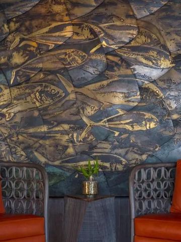 Kunstvolle Wandgestaltung mit Fischmotiven und zwei Ledersesseln