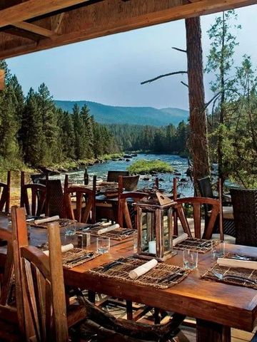 Rustikale Außenterrasse mit Holztischen und Flussblick im Resort