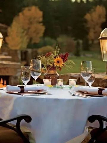 Romantischer Terrassentisch mit Kerzen und Laternen bei Sonnenuntergang