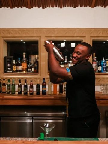 Barkeeper mixt Cocktails in stilvoller Hotelbar mit Spirituosenregalen
