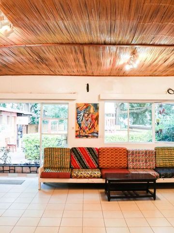 Lichtdurchflutete Lounge mit bunten Sitzkissen und Holzdach