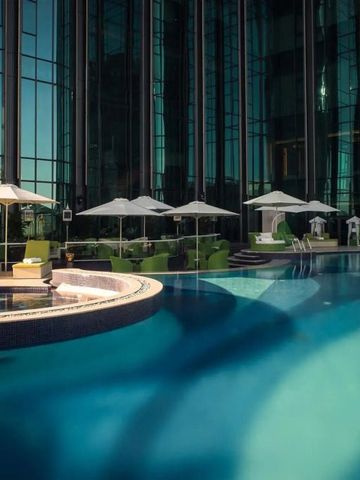 Hotelpool mit eleganten Sonnenliegen und modernem Glasgebäude im Hintergrund
