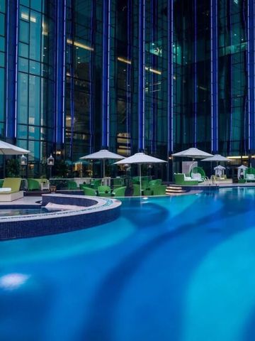 Beleuchteter Hotelpool bei Nacht mit eleganten Sonnenschirmen