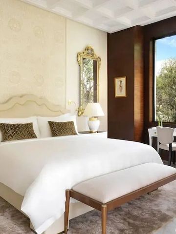 Luxuriöses Hotelzimmer mit großem Bett und Blick auf den Garten.