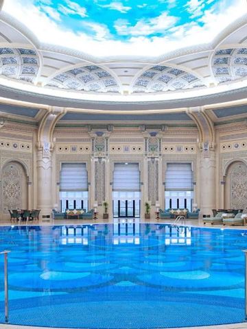 Beeindruckender Innenpool in Kuppelbau mit opulenter Dekoration und blauer Beleuchtung.