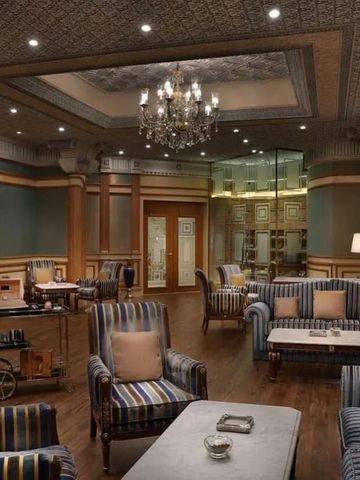 Elegante Lounge mit gestreiften Sesseln und Kronleuchter im Ritz-Carlton, Riyadh.