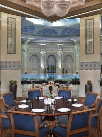 Luxuriöses Restaurant mit aufwändiger Decke und gedeckten Tischen.