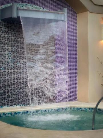 Whirlpool mit Wasserfall und Mosaikfliesen im Spa