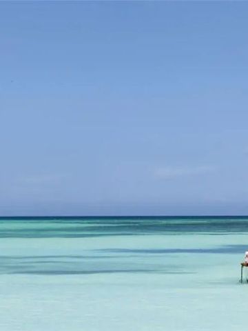 Kleines Boot auf ruhigem, türkisfarbenem Meer unter klarem Himmel.