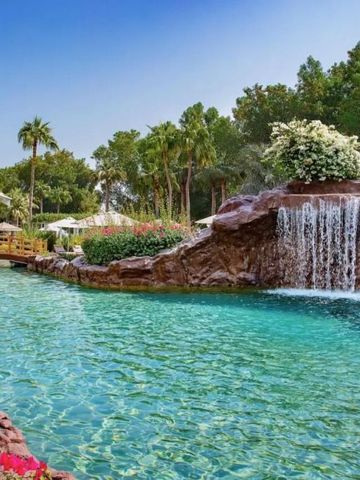 Idyllischer Außenpool mit Wasserfall und üppiger Vegetation im The Ritz-Carlton Doha