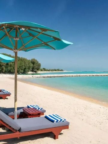 Sonnenliegen mit Sonnenschirmen am weißen Sandstrand des The Ritz-Carlton Doha