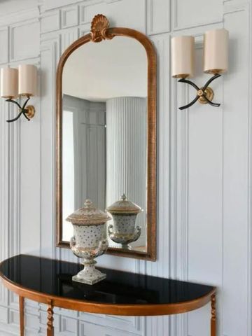 Klassischer Gang mit Spiegel und eleganten Wandlampen