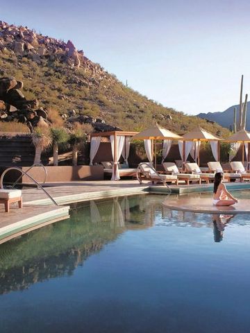 Infinity-Pool in malerischer Wüstenlandschaft mit Cabanas und Liegen.
