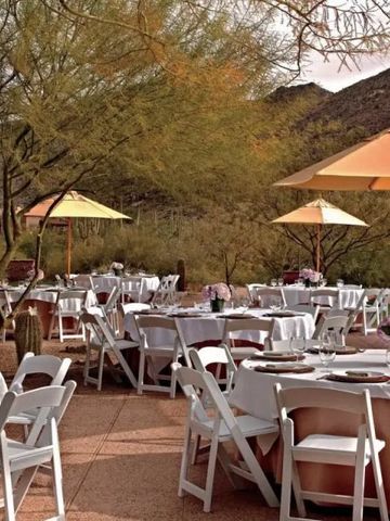 Elegante Außenterrasse mit gedeckten Tischen unter Sonnenschirmen, umgeben von Natur