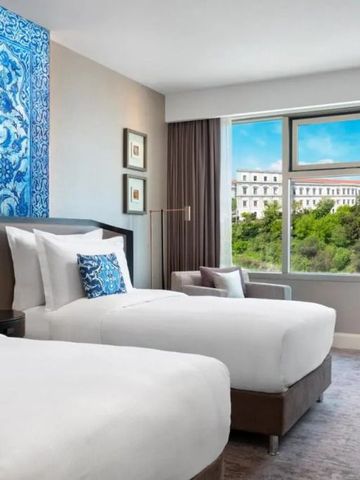 Moderne Hotel-Suite mit zwei Betten und Blick auf grüne Umgebung.