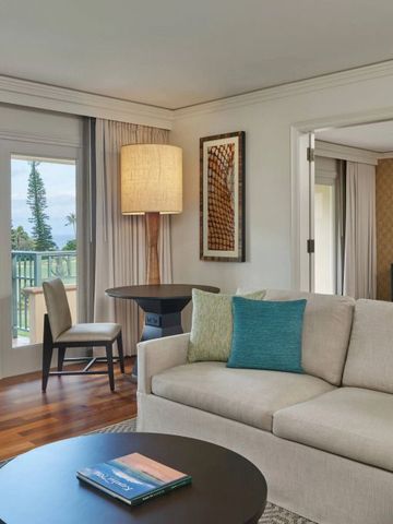 Luxuriöses Wohnzimmer in einer Suite mit Sofa und Blick auf eine tropische Landschaft