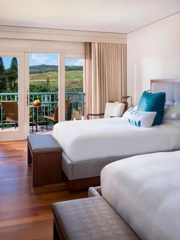 Zwei Betten in einem stilvoll eingerichteten Raum mit Balkon und Naturblick