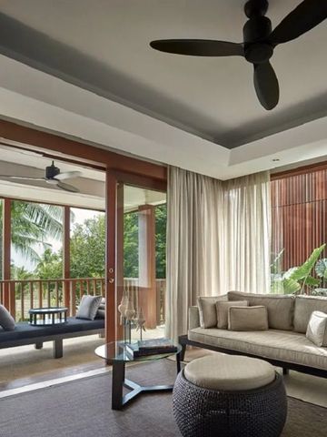 Geräumiger Wohnbereich einer Suite mit moderner Einrichtung und Balkon mit Gartenblick